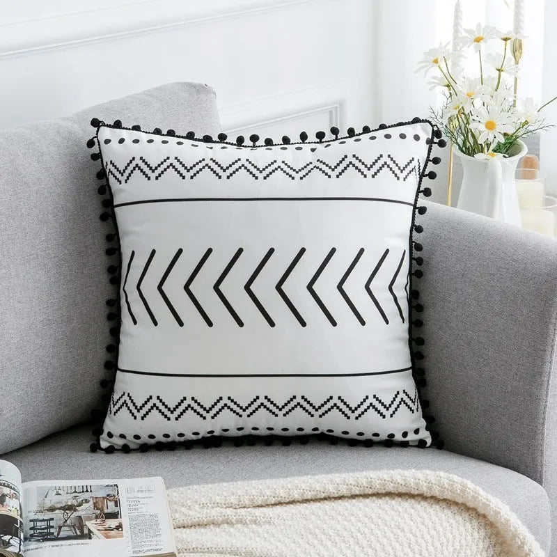 Bohemian style decorative throw pillow with polyester cover in light grey on a sofa.
