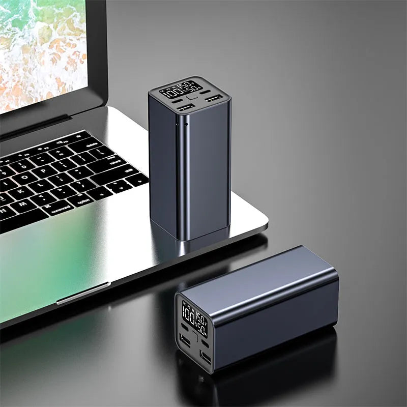 Black metal 65W laptop power bank with 20000mAh capacity showing size next to a laptop.