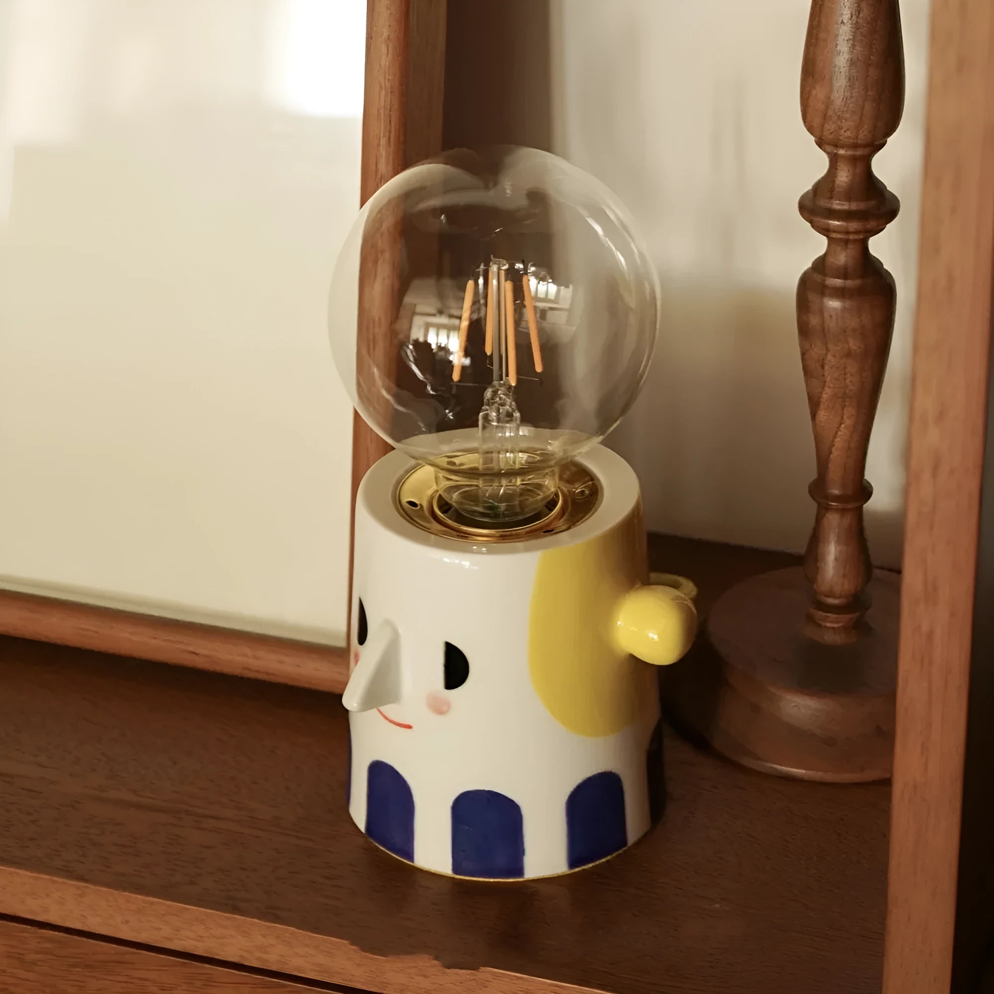 Handmade white ceramic table lamp with a spherical ball-shaped shade on a wooden surface.