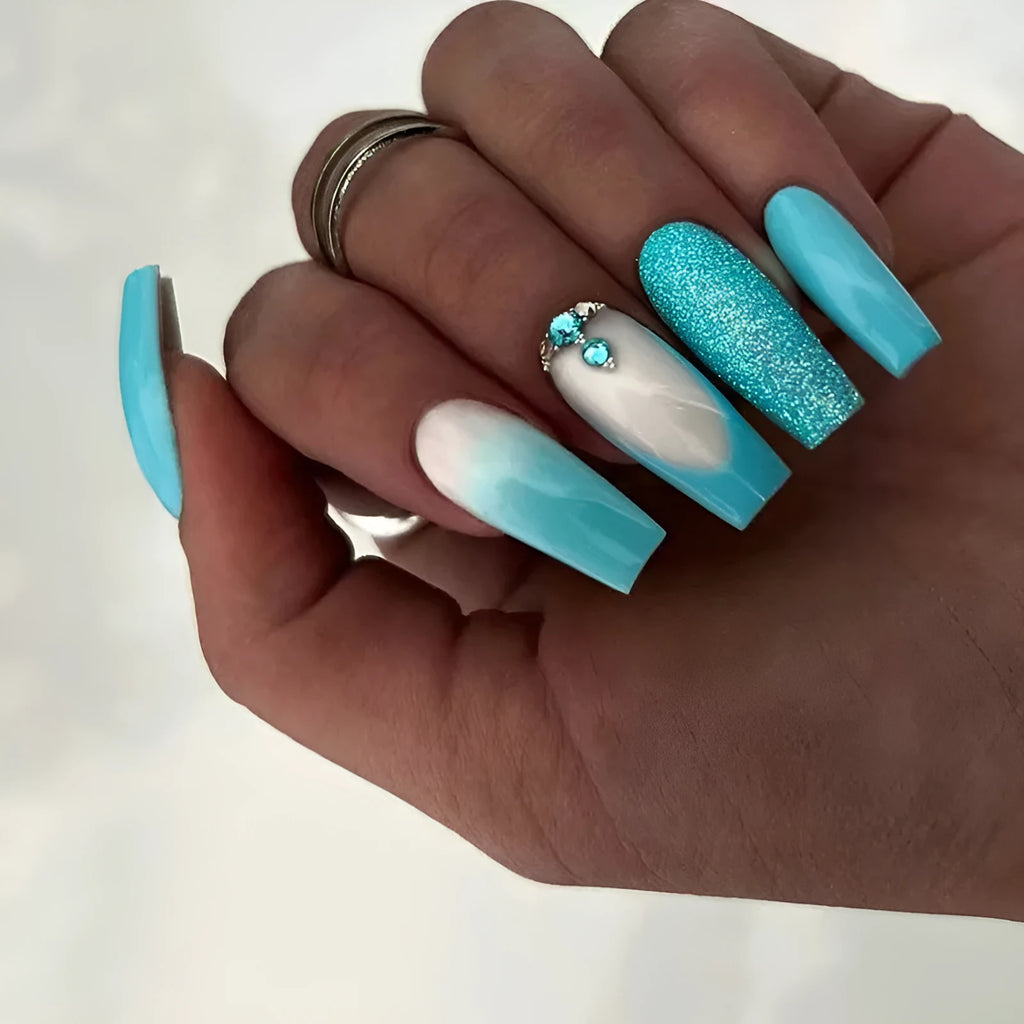 Long ballet shaped false nails in solid blue diamond colour with glitter adhesive glue.