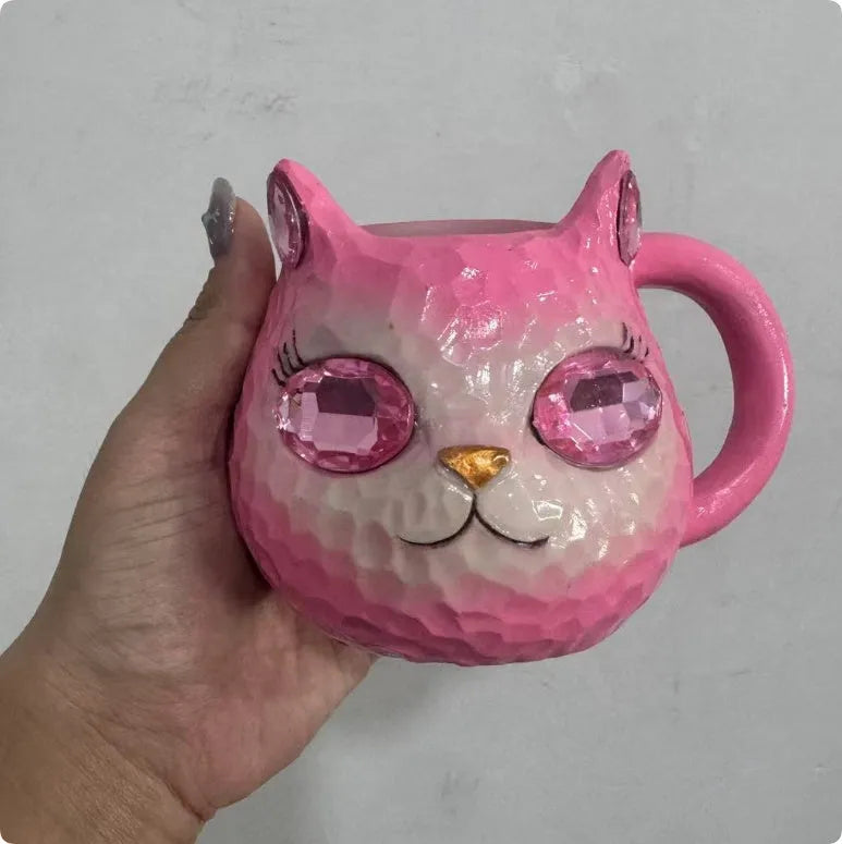 Colourful resin cat cup figurine on a shelf, shown in purple, green, blue, and pink colour options.