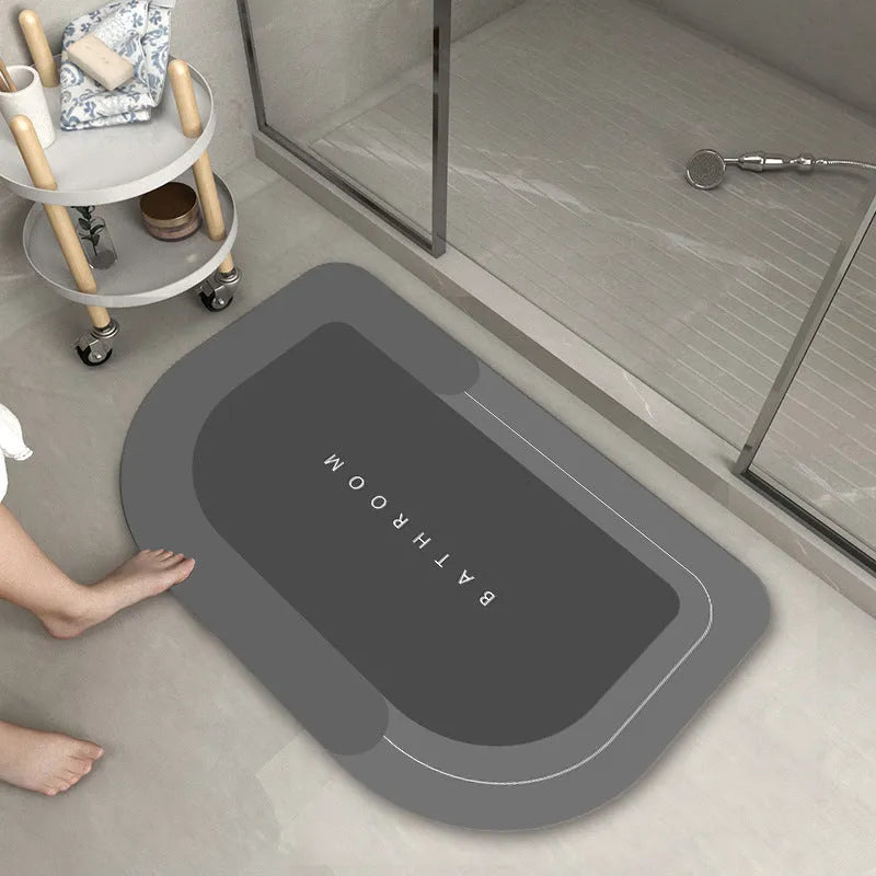 Machine-woven blended bathroom floor mat in blue, shown in an oval shape on a tiled floor.