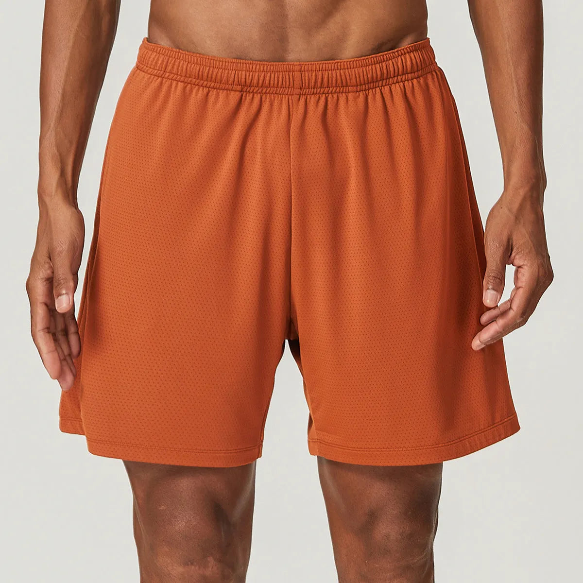 Men's quick-dry double-layer running shorts in a brick red colour on a mid-waist fit model.