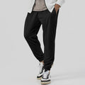 Man wearing grey loose tapered track sweatpants with a micro-elastic cotton blend fabric.