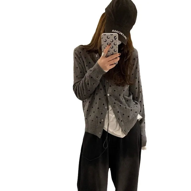 Women's loose grey dot patterned knitted cardigan with crocheted flower details on the front.