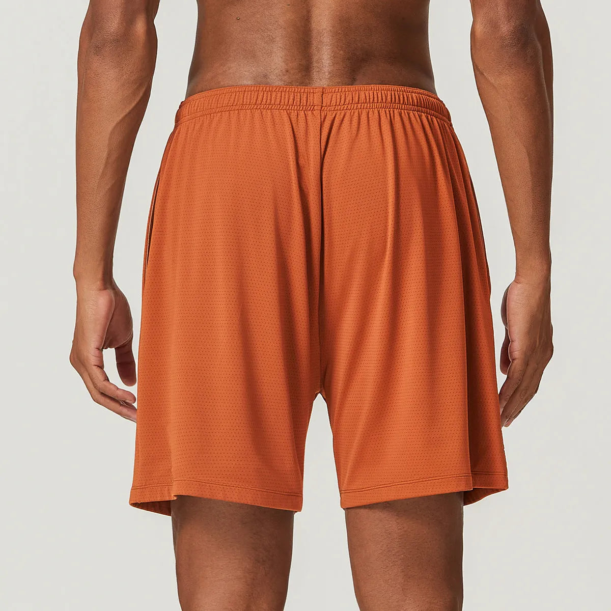Men's quick-dry double-layer running shorts in a brick red colour on a mid-waist fit model.