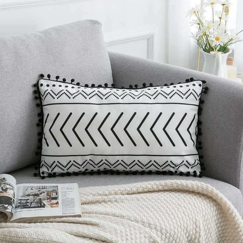 Bohemian style decorative throw pillow with polyester cover in light grey on a sofa.