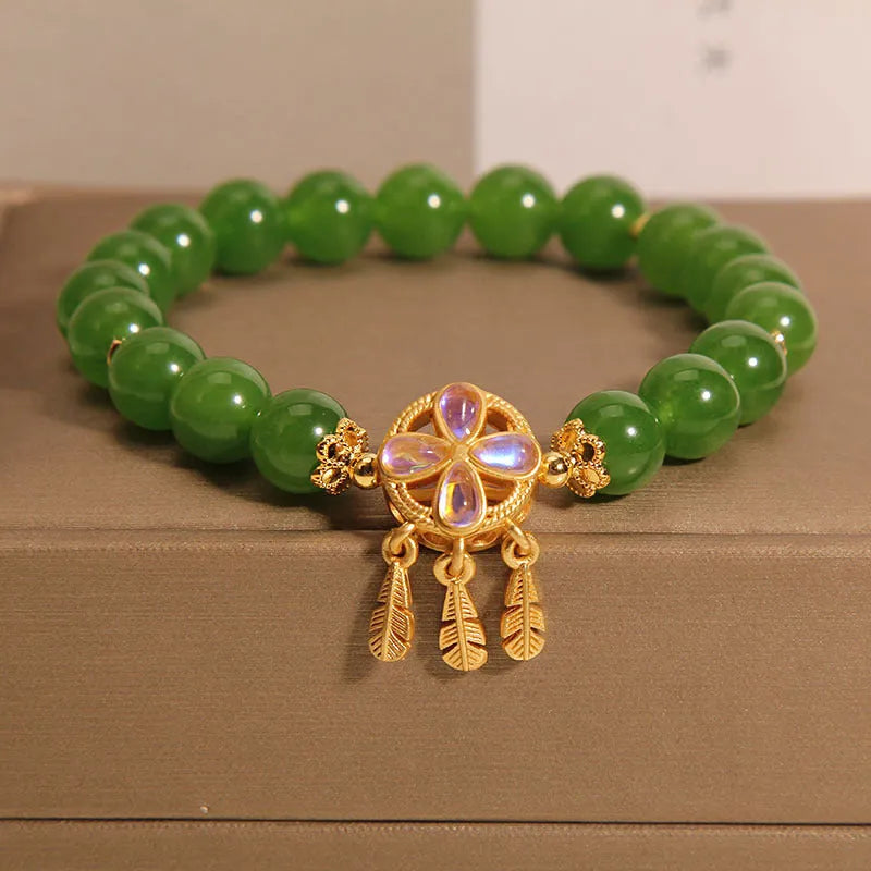 Green Jasper crystal bracelet with a four-leaf clover dream catcher pendant on a woman's wrist.