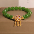Green Jasper crystal bracelet with a four-leaf clover dream catcher pendant on a woman's wrist.