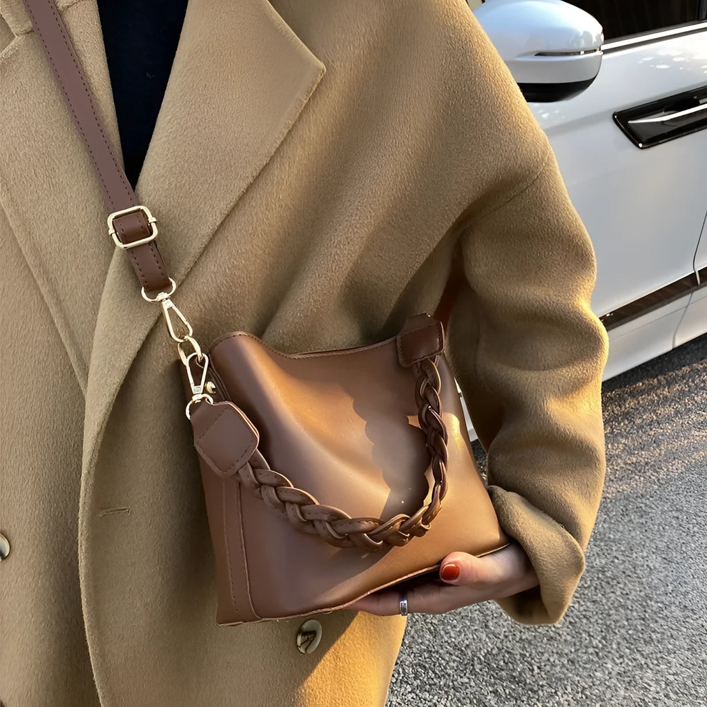 Retro style khaki crossbody bucket bag with weaving detail on the front.