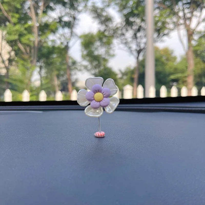 Small colourful plastic swing car decoration on a car dashboard, showing blue, green, pink, purple, and yellow colour options.
