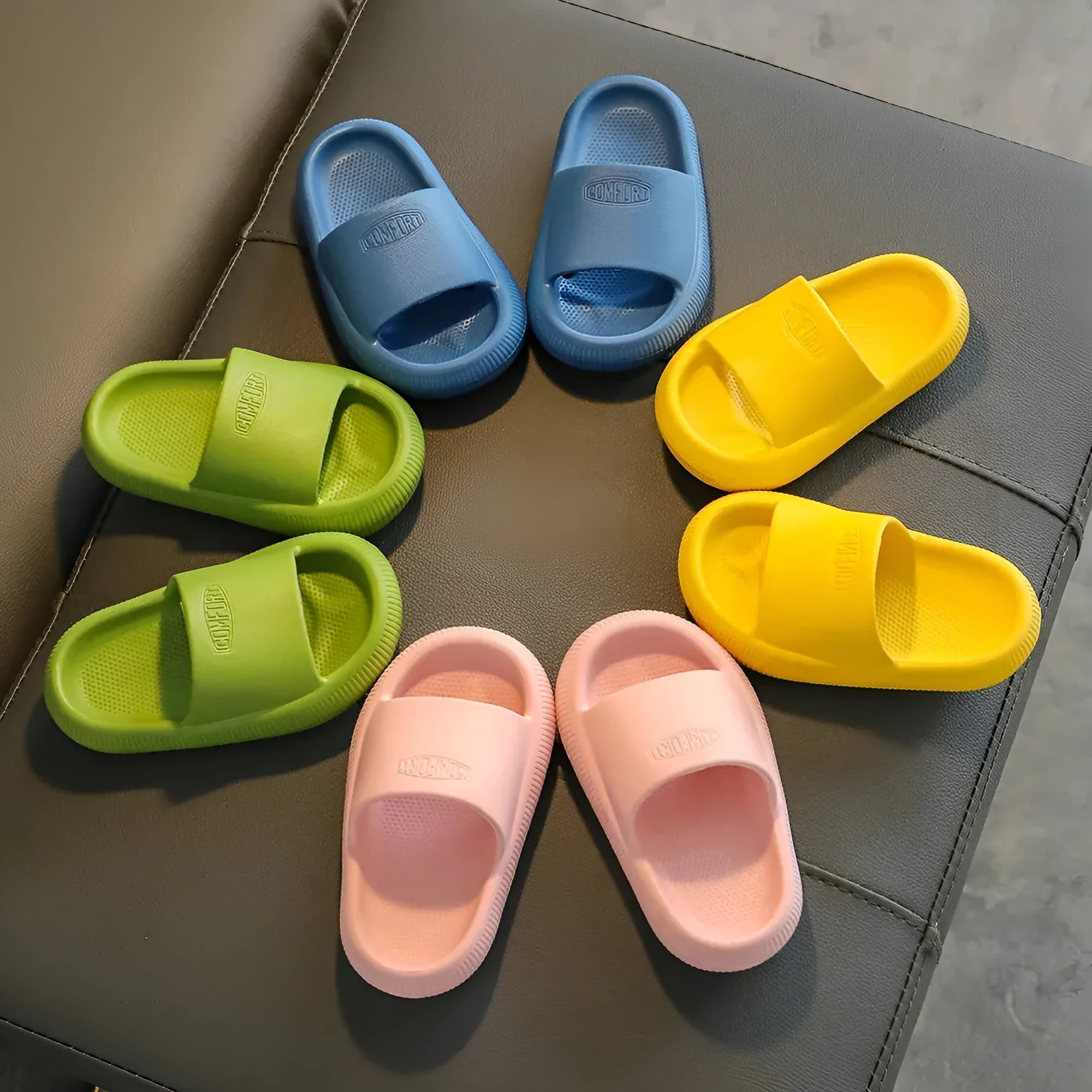 Colourful children's EVA slippers with textured sole, shown in blue, green, orange, pink, and yellow.