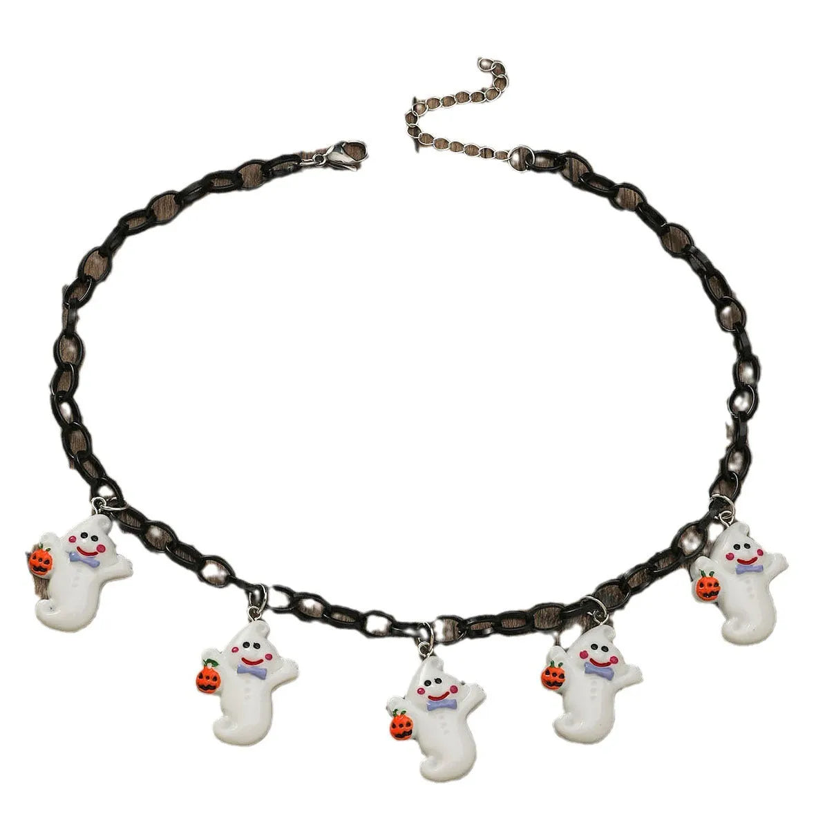 A Halloween necklace with an acrylic pumpkin and skull pendant on a clavicle chain