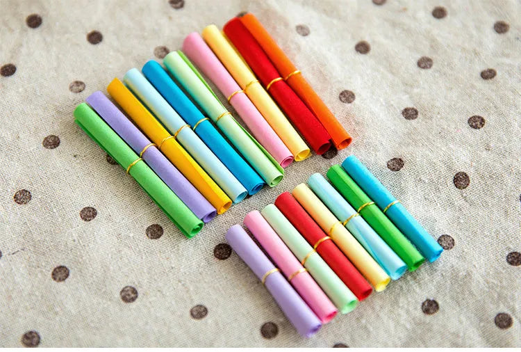 Colourful mini letter paper scrolls with eyelet holes for bottle messages in multiple sizes