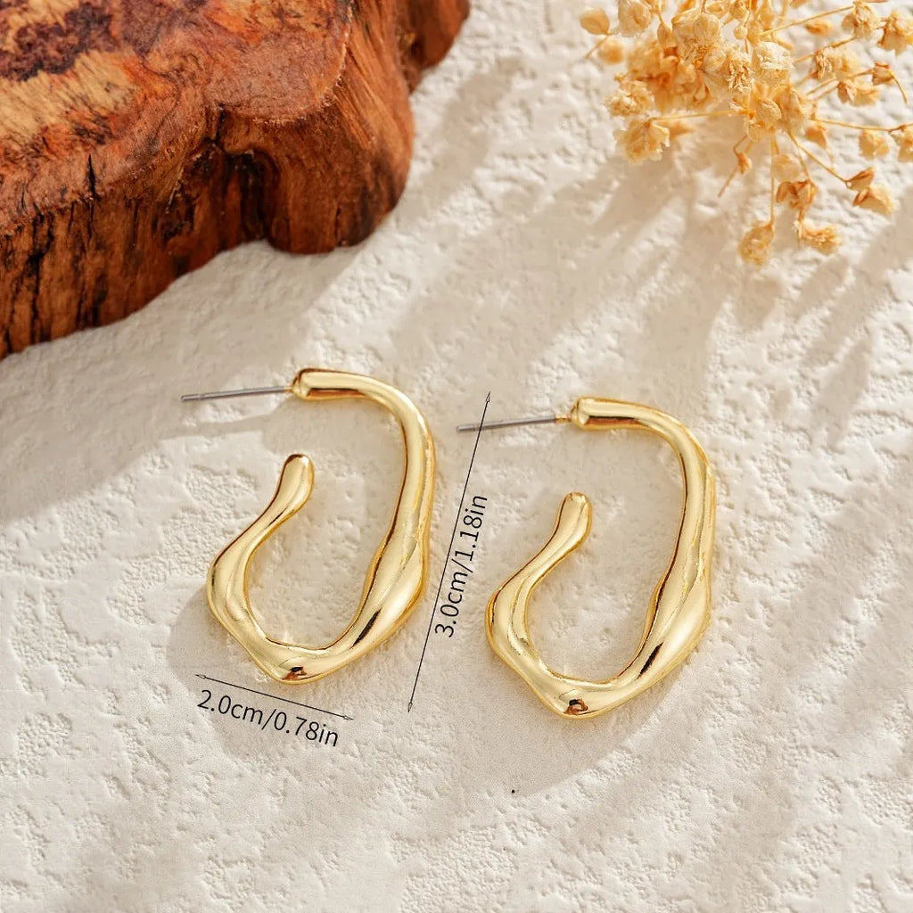 Gold irregular shaped minimalist earrings for women with a geometric silhouette on a plain background.
