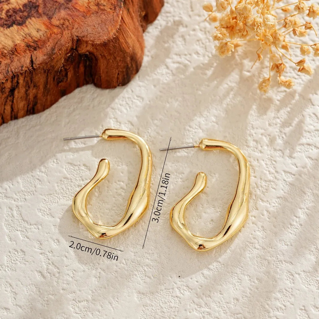 Gold irregular shaped minimalist earrings for women with a geometric silhouette on a plain background.