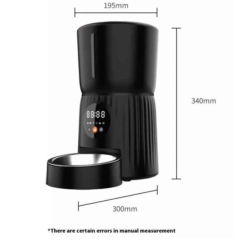 Black automatic pet feeder with digital timer display and remote control on a table.