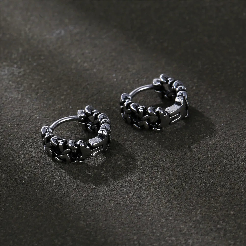 Close-up of a pair of men's geometric copper hip hop earrings on a dark background.