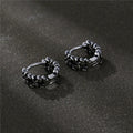 Close-up of a pair of men's geometric copper hip hop earrings on a dark background.