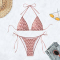 Green backless women's bikini with halter neck strap lying flat.