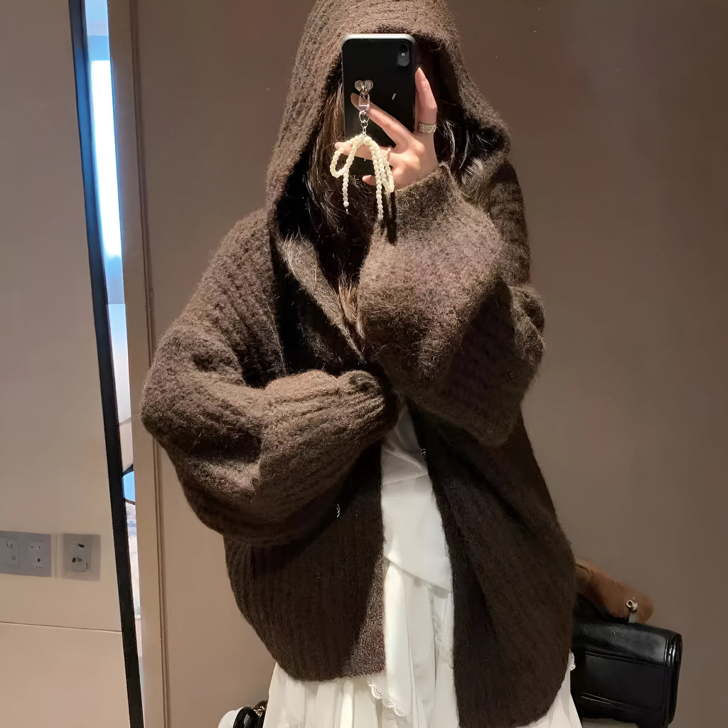 Woman wearing a brown retro-style chunky knit hooded cardigan with a loose fit.