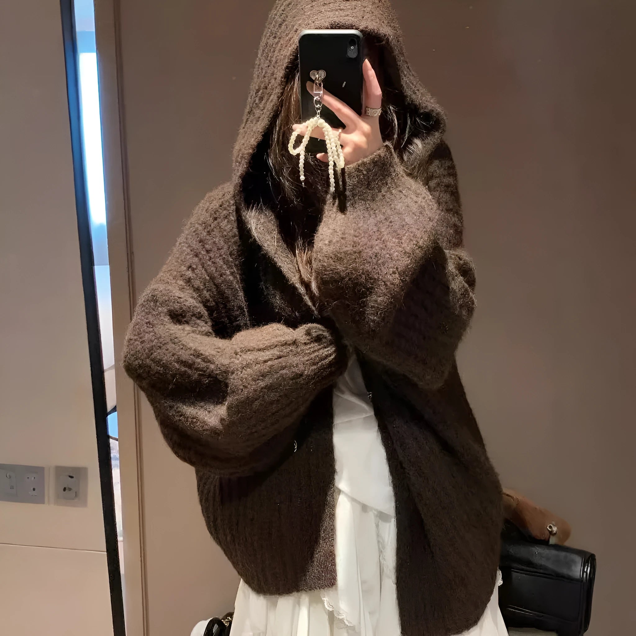 Woman wearing a brown retro-style chunky knit hooded cardigan with a loose fit.