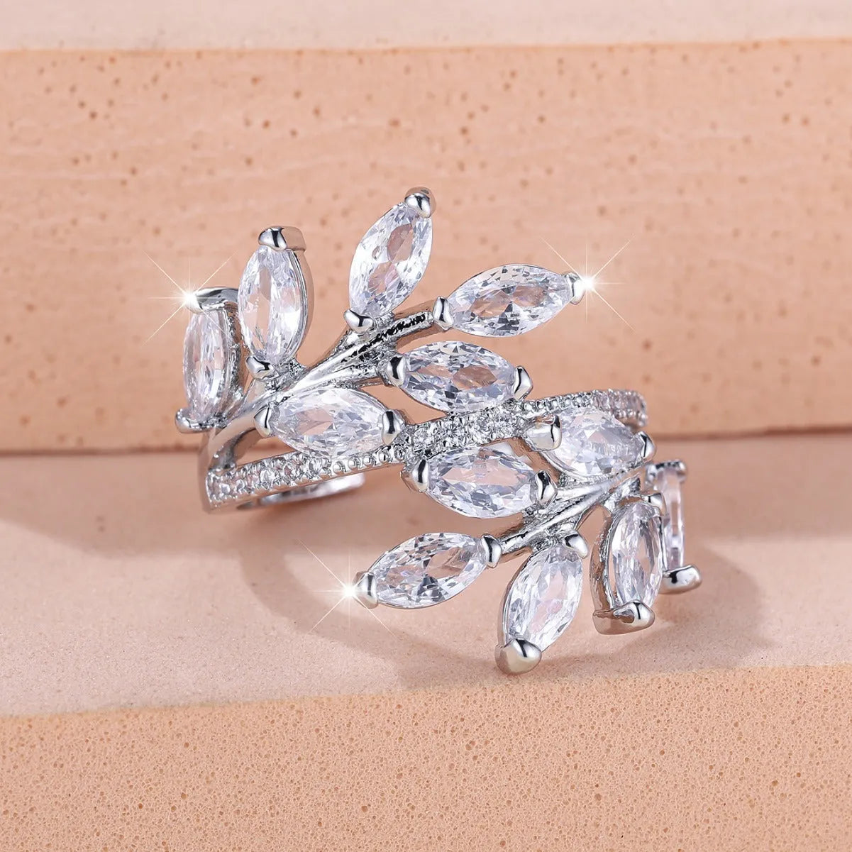 Adjustable copper leaf ring with a central zircon stone on a finger, showing rose gold and platinum colour options.