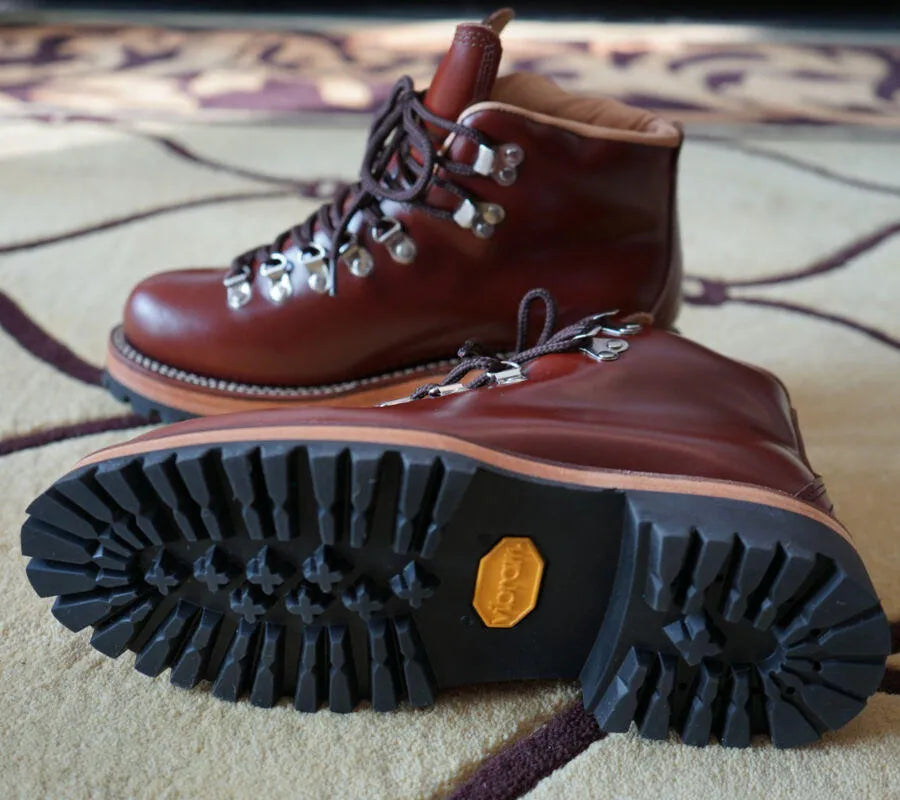Men's brown leather city hiking boots with lace-up closure on a wooden surface
