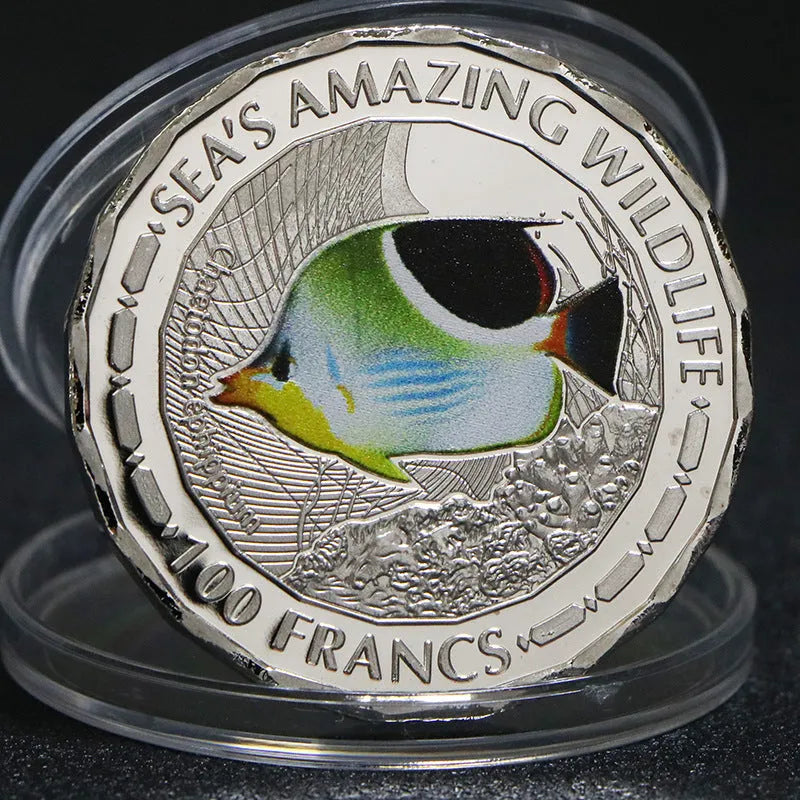 Set of eight silver plated commemorative coins with tropical fish and marine animal designs, 40mm diameter, in acrylic box