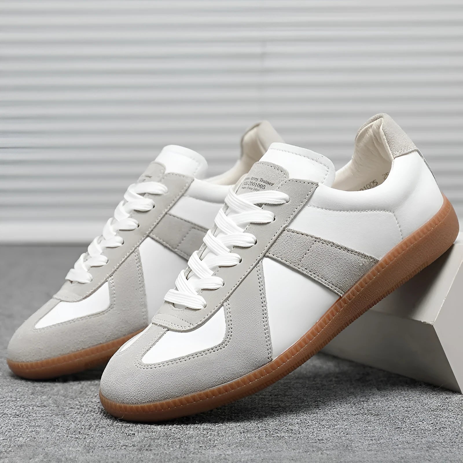 White low-top retro sneakers with round toe and lace-up front on a flat rubber sole.
