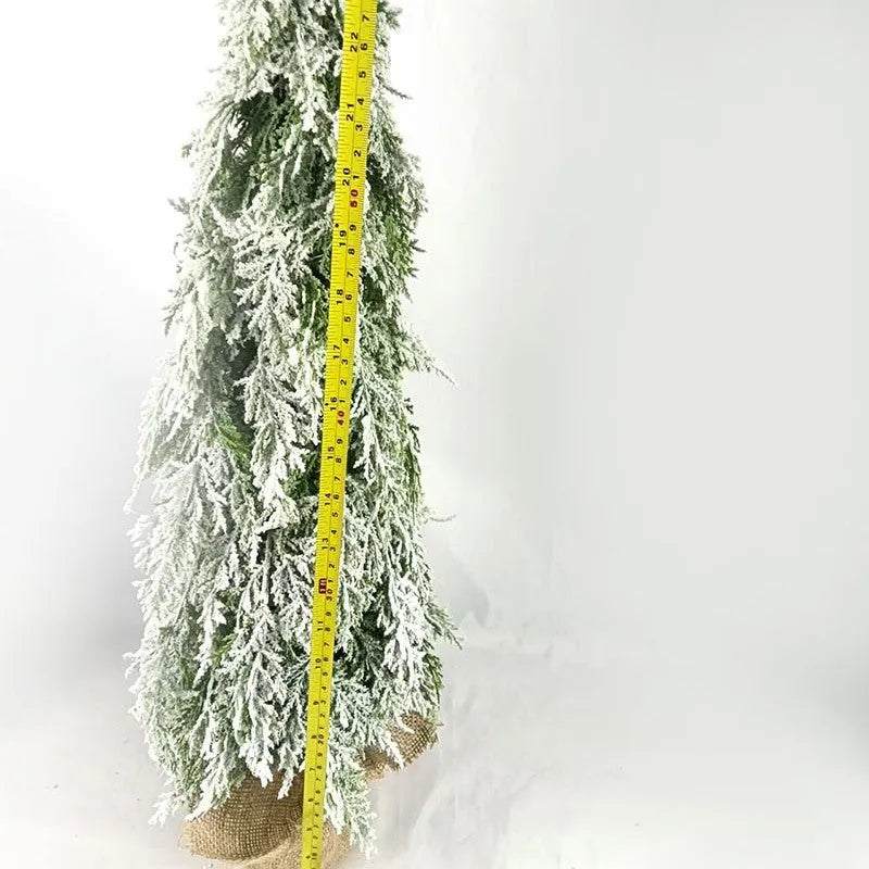 Small 24-inch plastic Christmas tree with LED lights and snow-covered branches on desktop
