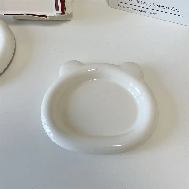 White ceramic plate with cartoon bear doodle design, shown next to round toot design plate, both microwave safe.