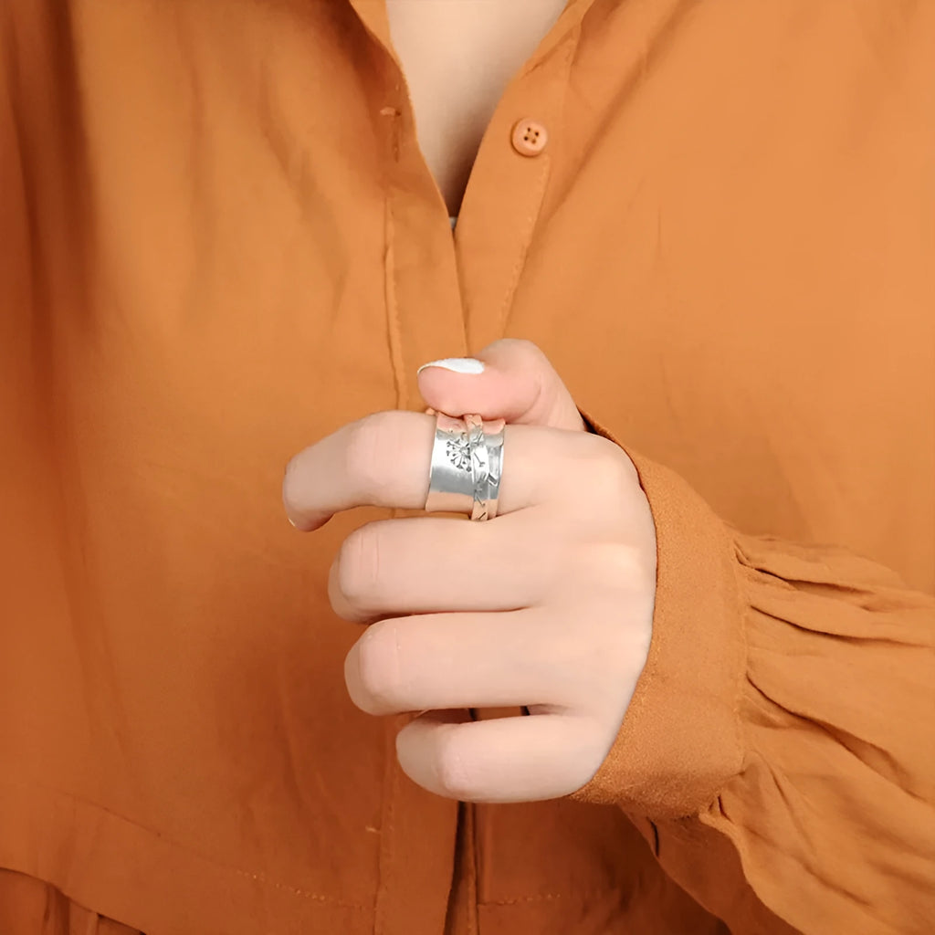 Silver rotating flower ring with movable petals on a finger, showing the kinetic jewellery design