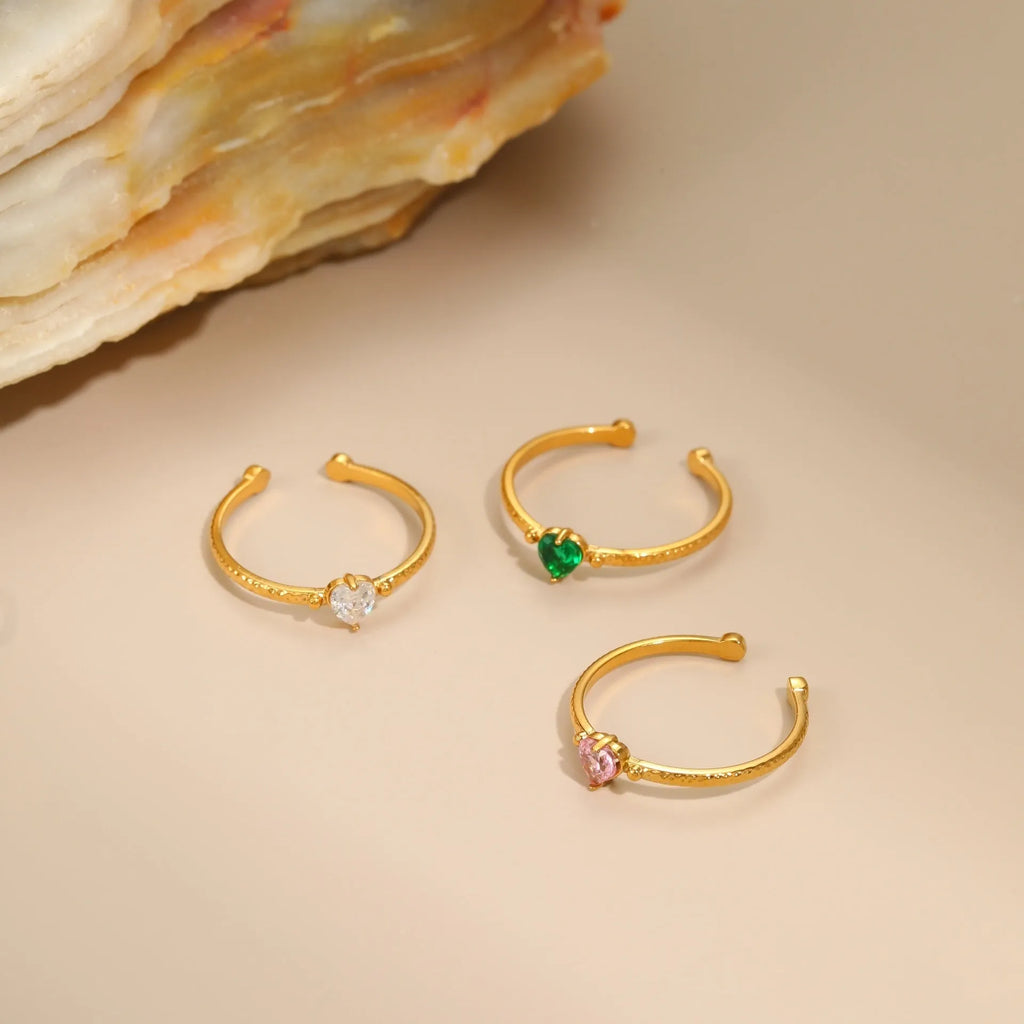 Geometric open-ended heart-shaped stainless steel ring with inlaid zircon detail in white, pink, or green.