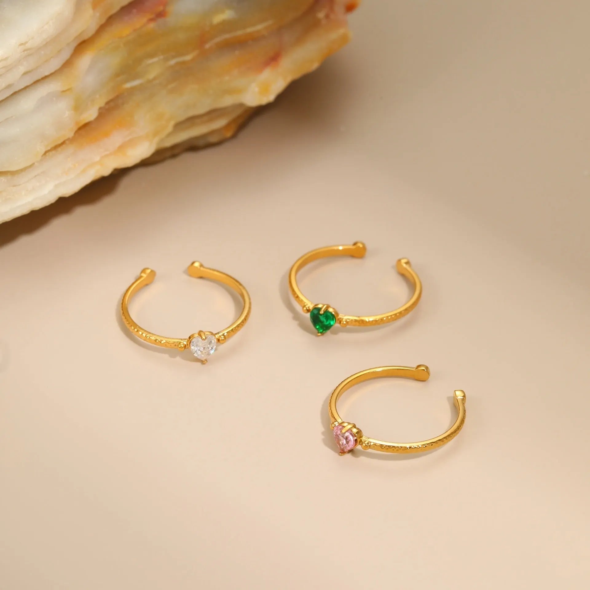 Geometric open-ended heart-shaped stainless steel ring with inlaid zircon detail in white, pink, or green.