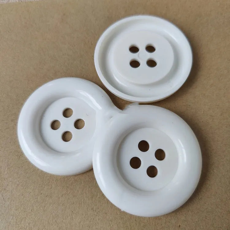 Oversized round edge plastic button with four holes in various colours and diameter sizes