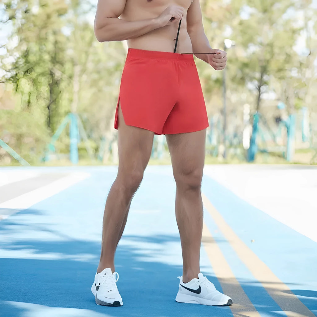 Men's red off-road running shorts with high waist and loose fit on a grey background.