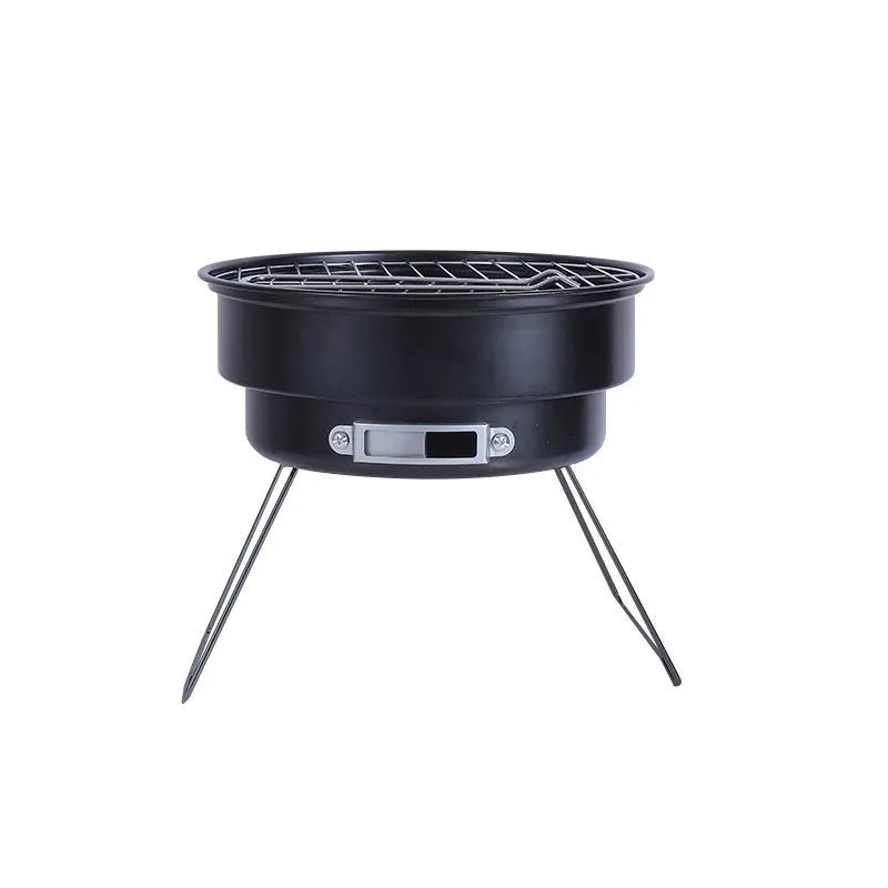 Small round metal folding stove with barbecue grill and mesh, set up for outdoor cooking.