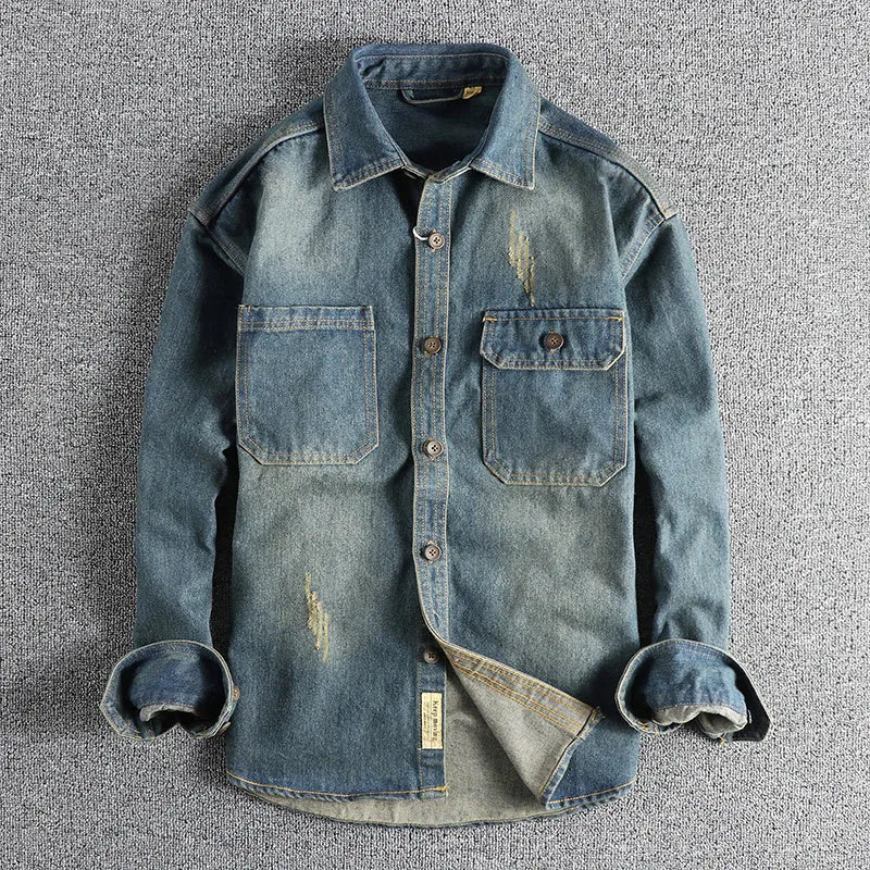Man wearing a light blue vintage washed denim shirt with a loose fit and long sleeves.