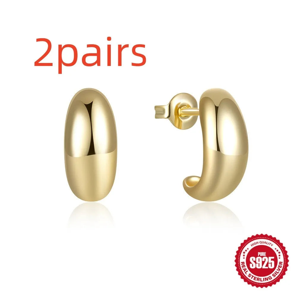 Close-up of a glossy C-shaped sterling silver stud earring on a gold background.