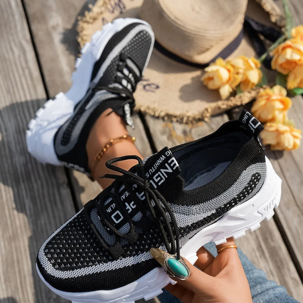 Women's Flyknit mesh lace-up sneakers in grey and white with a low rubber sole.