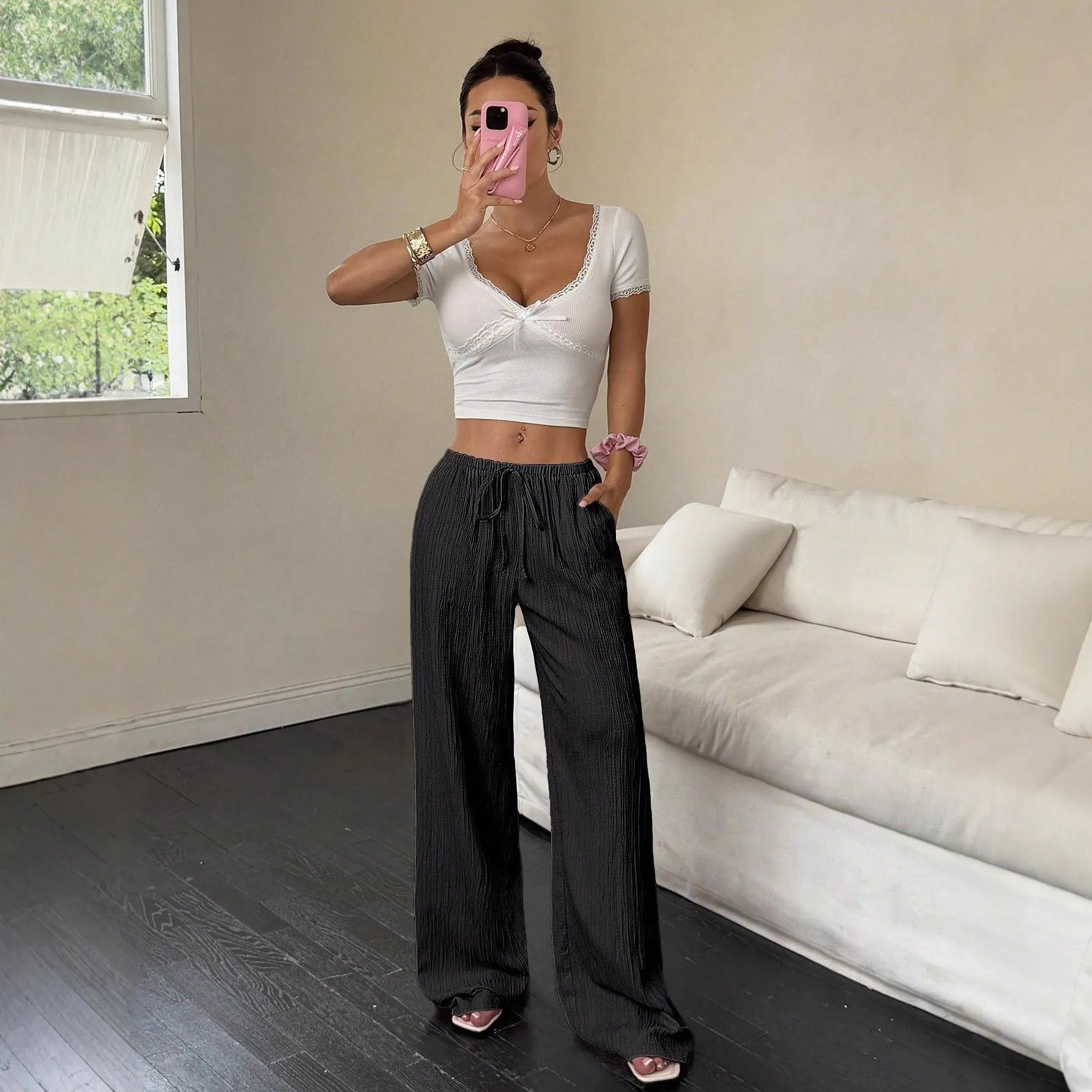 Women's black wide-leg trousers with a front lace-up waist detail on a neutral background.