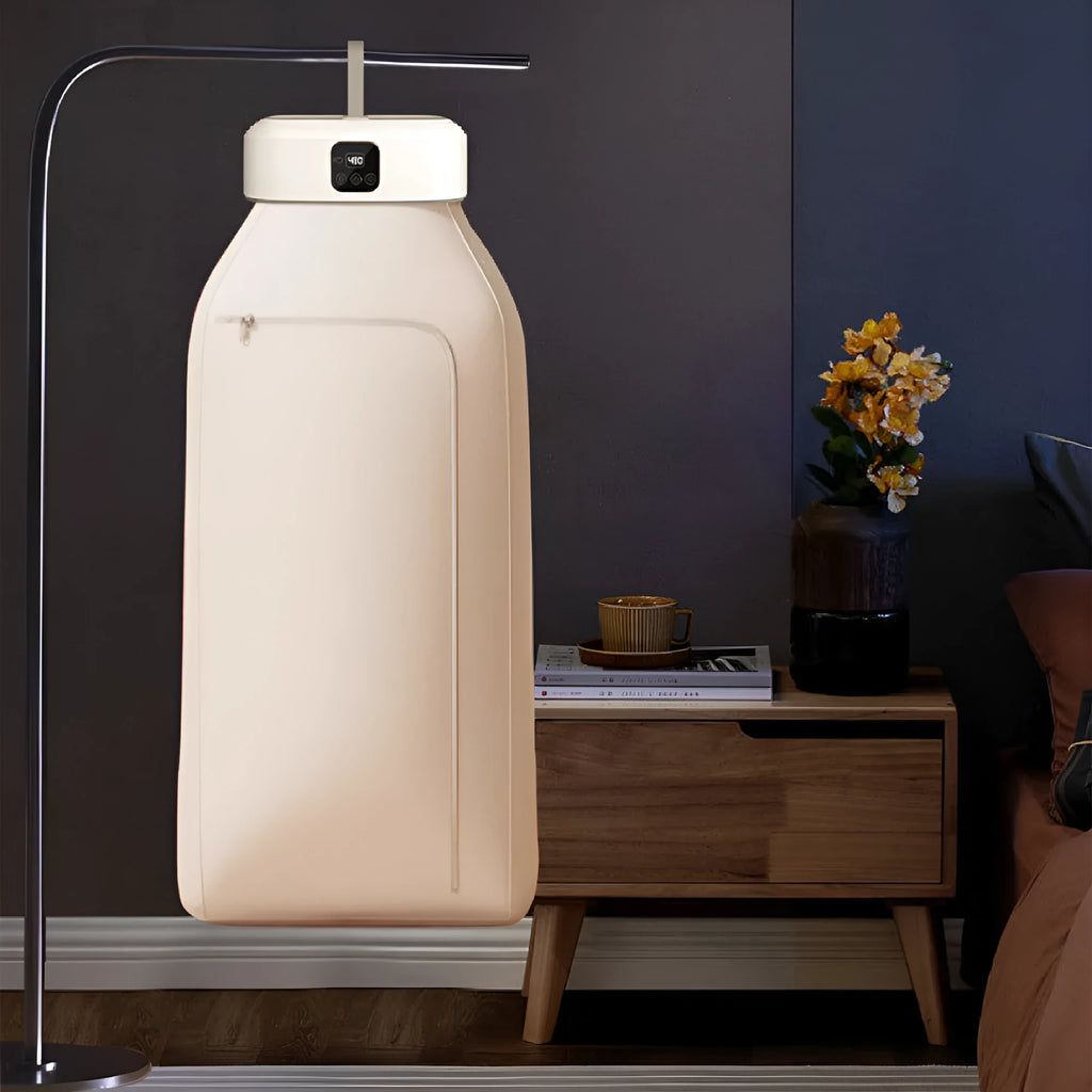 White cylindrical portable laundry drier dryer with remote control on a countertop.