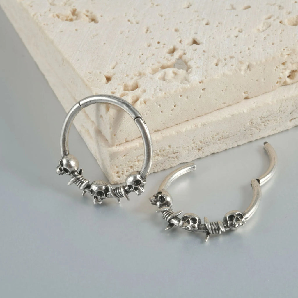 A pair of antique silver copper punk earrings featuring three small detailed ghost heads on a horizontal bar.
