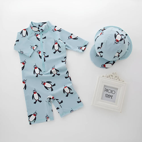 Boy in penguin print long sleeve one-piece swimsuit and matching swimming cap