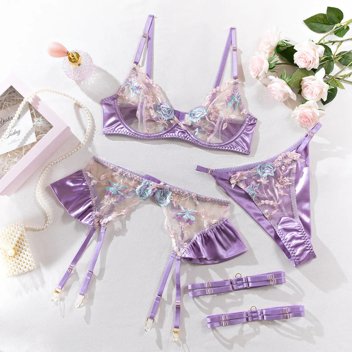 Light purple satin lingerie four-piece set with decorative embroidery on a hanger