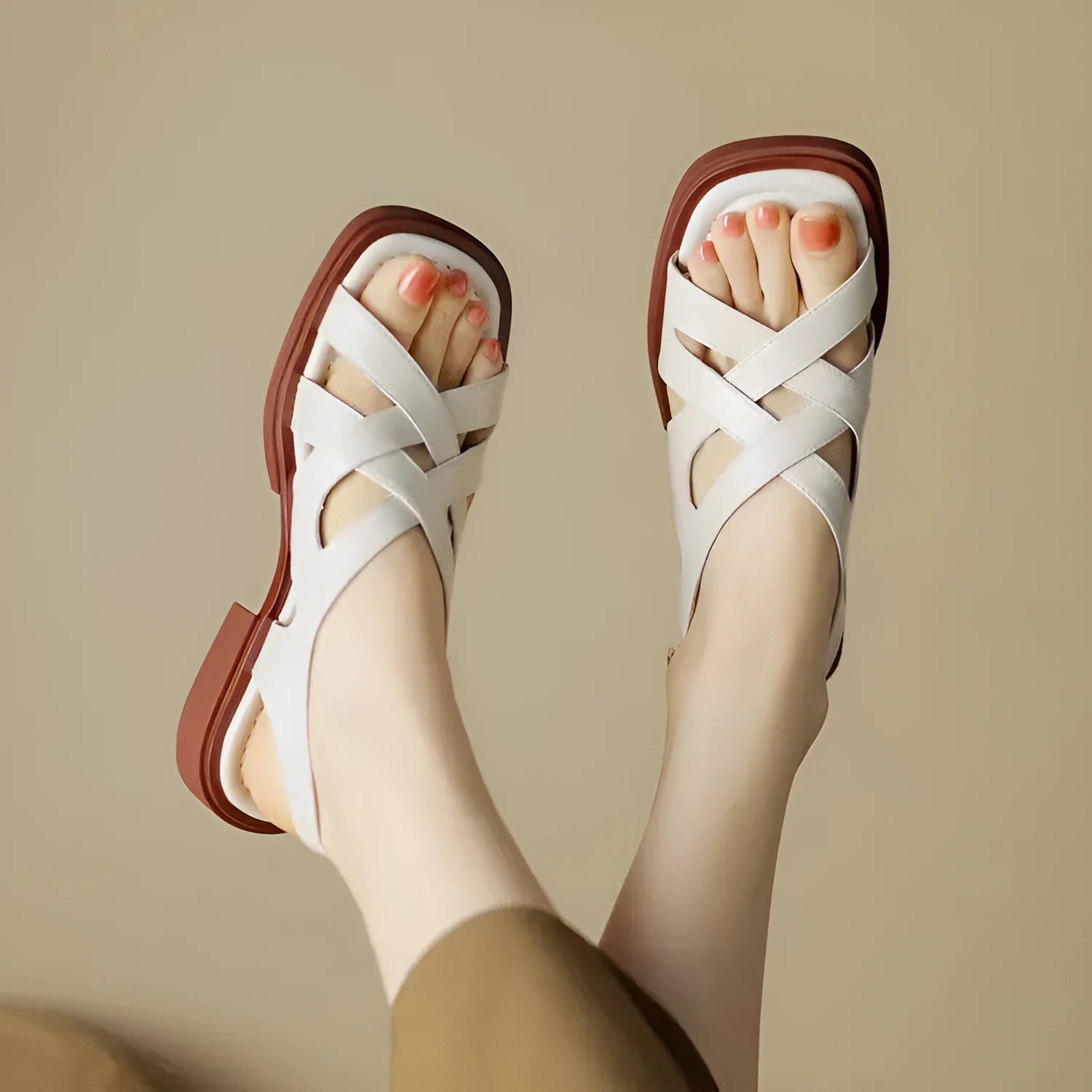 Women's black patent leather square toe sandals with a cross strap and low heel on a white background.