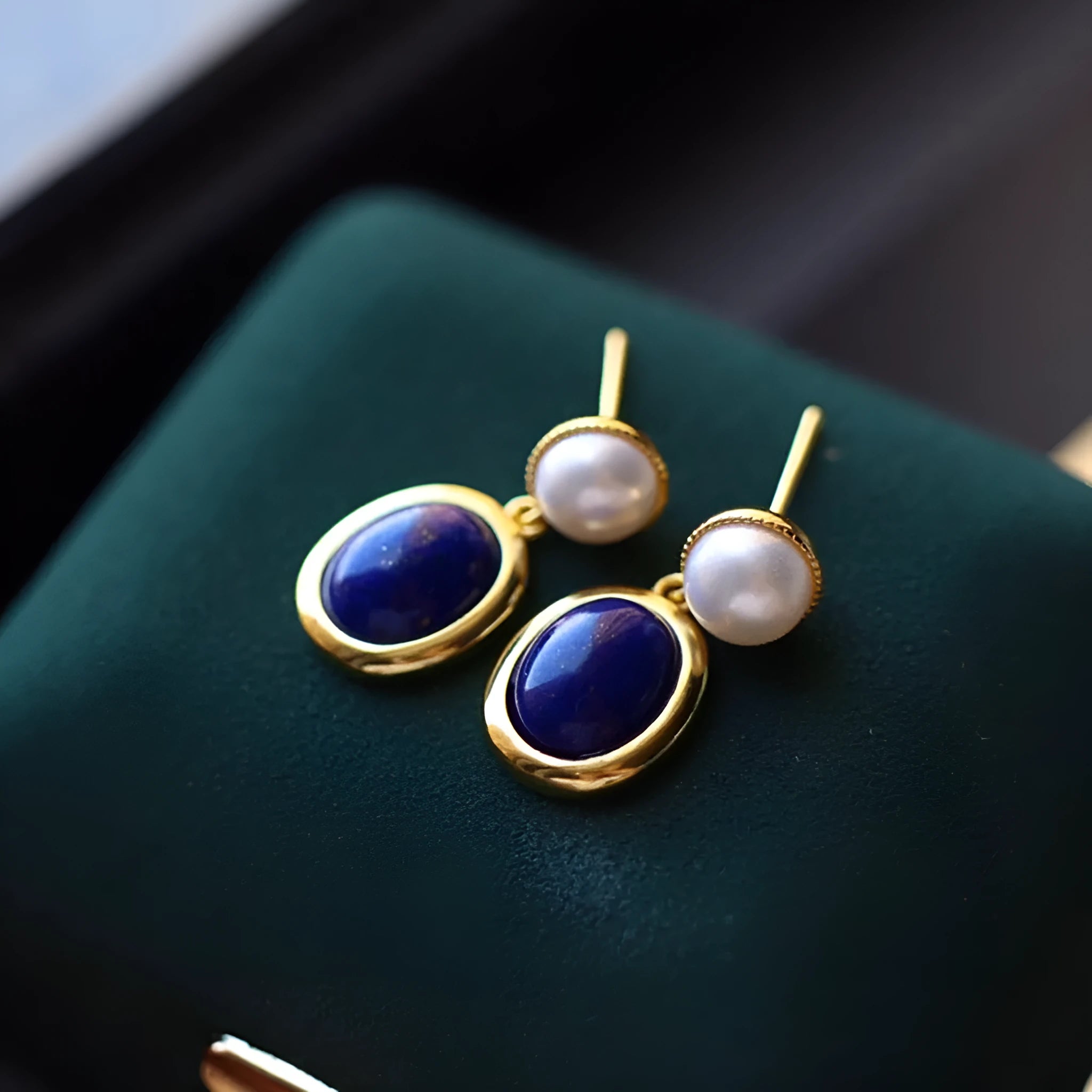 A pair of simple sterling silver earrings featuring deep blue lapis lazuli pearls.