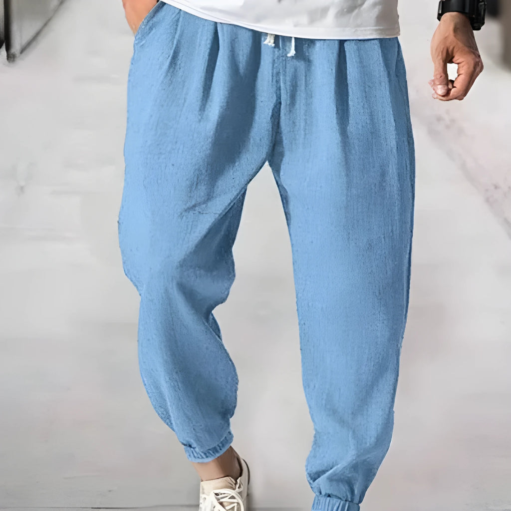 Men's loose-fit light green cotton casual trousers with a banded ankle cuff on a plain background.