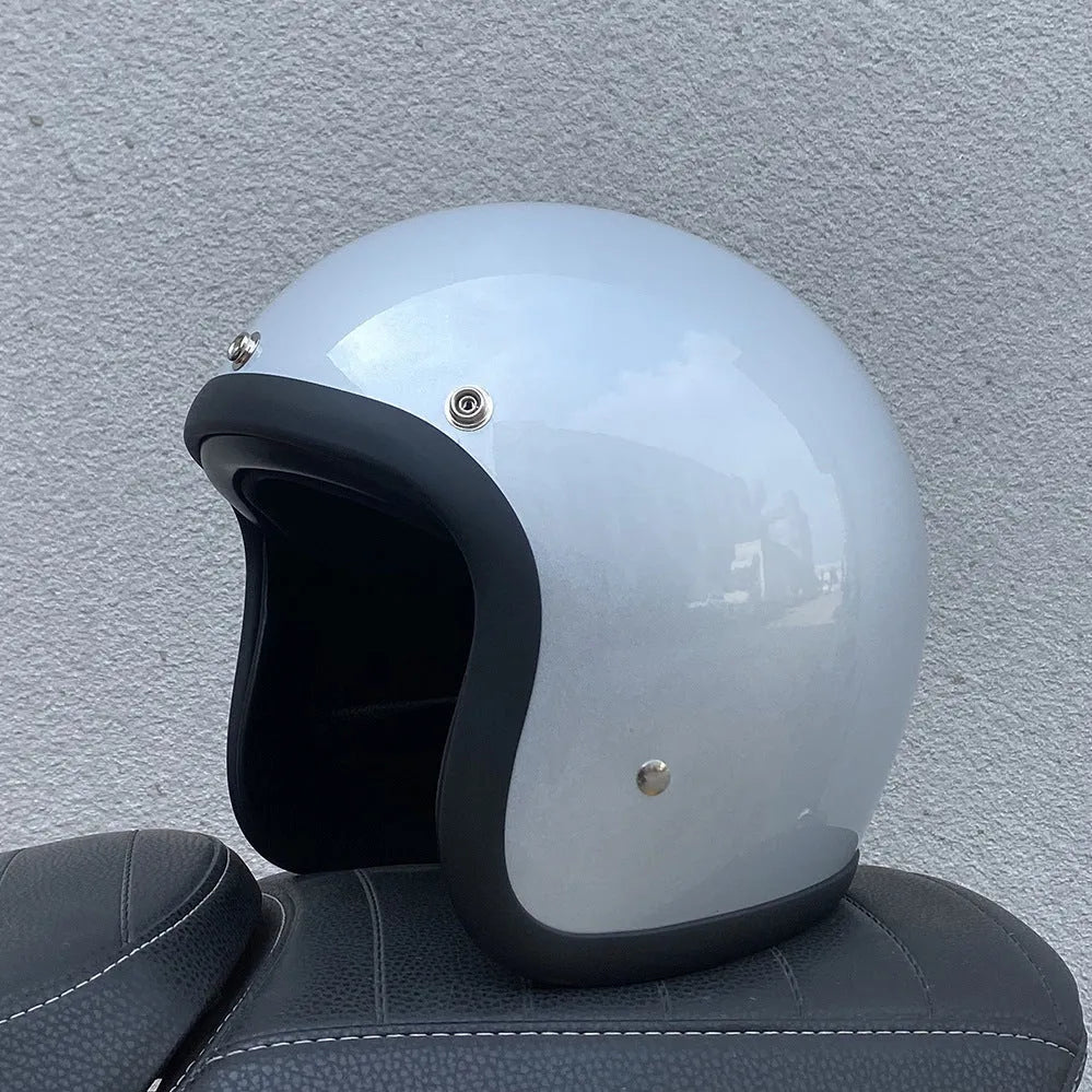 Retro-style open-face motorcycle helmet in fibreglass, shown in a choice of colours including Cement Grey and Matte Black Flower.